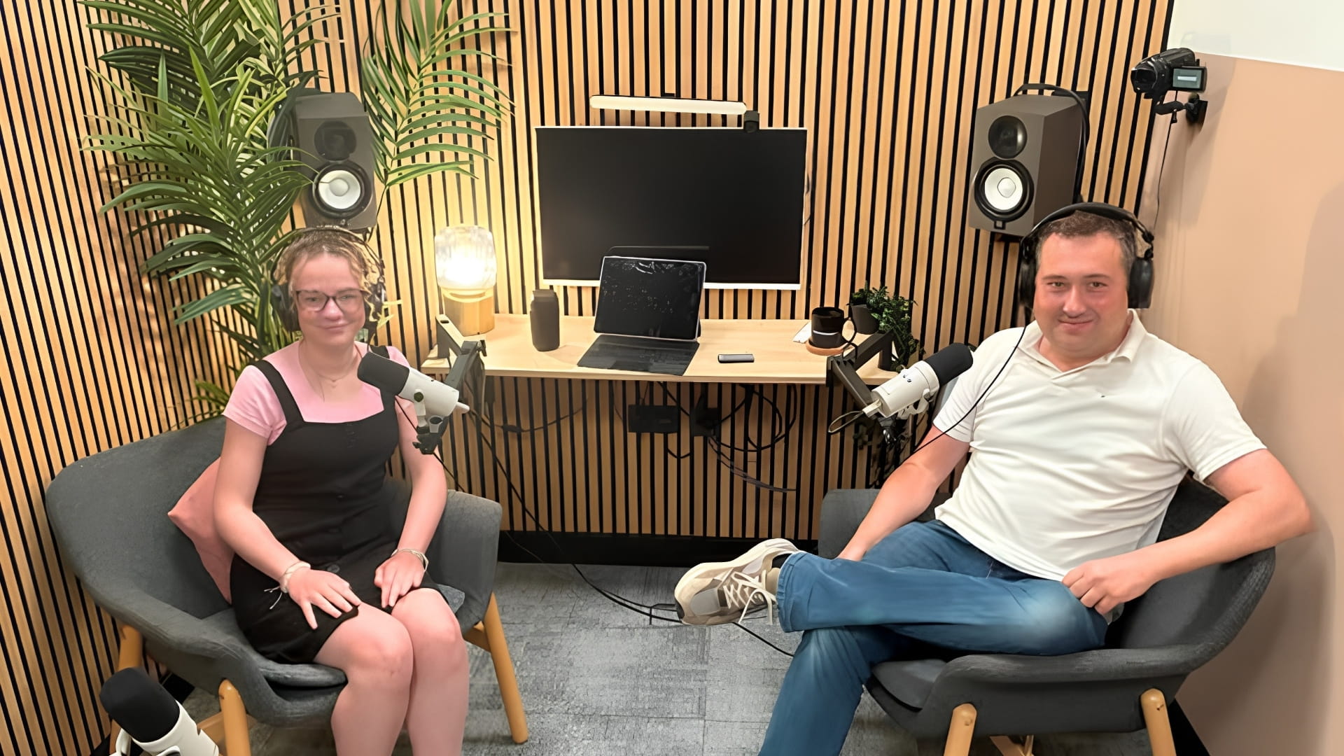 A man and a woman recording a podcast with microphones