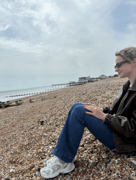 A female student sat on the beach looking out to sea