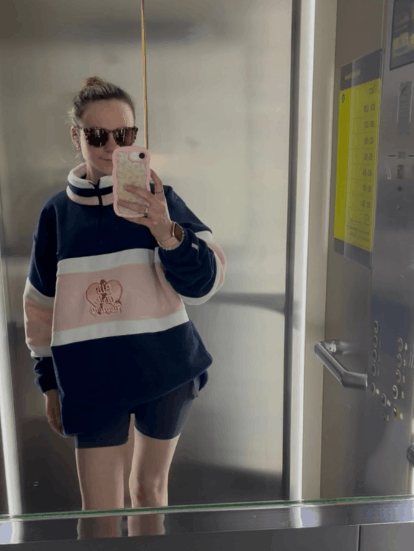 A female student taking a phone selfie wearing a society fleece